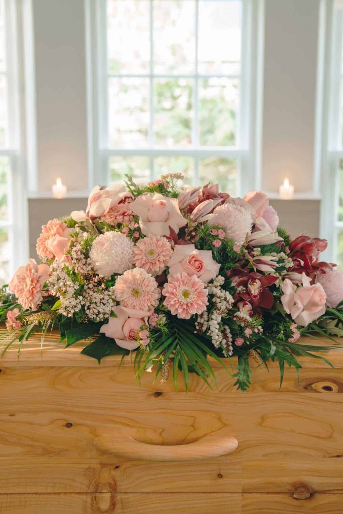 Pink and white flowers on a wooden casket